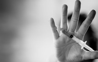 hand holding syringe - why do people relapse addiction concept