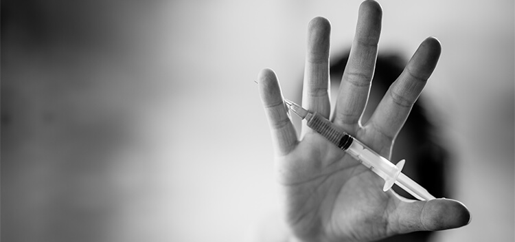 hand holding syringe - why do people relapse addiction concept