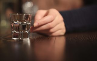 person with shot glass - national vodka day alcohol obsession