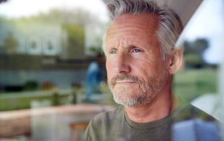 man looking out window thinking about relapse prevention strategies