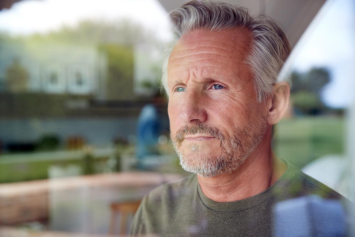 man looking out window thinking about relapse prevention strategies