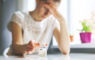 woman reaching for painkillers and in need of Painkiller Addiction Treatment