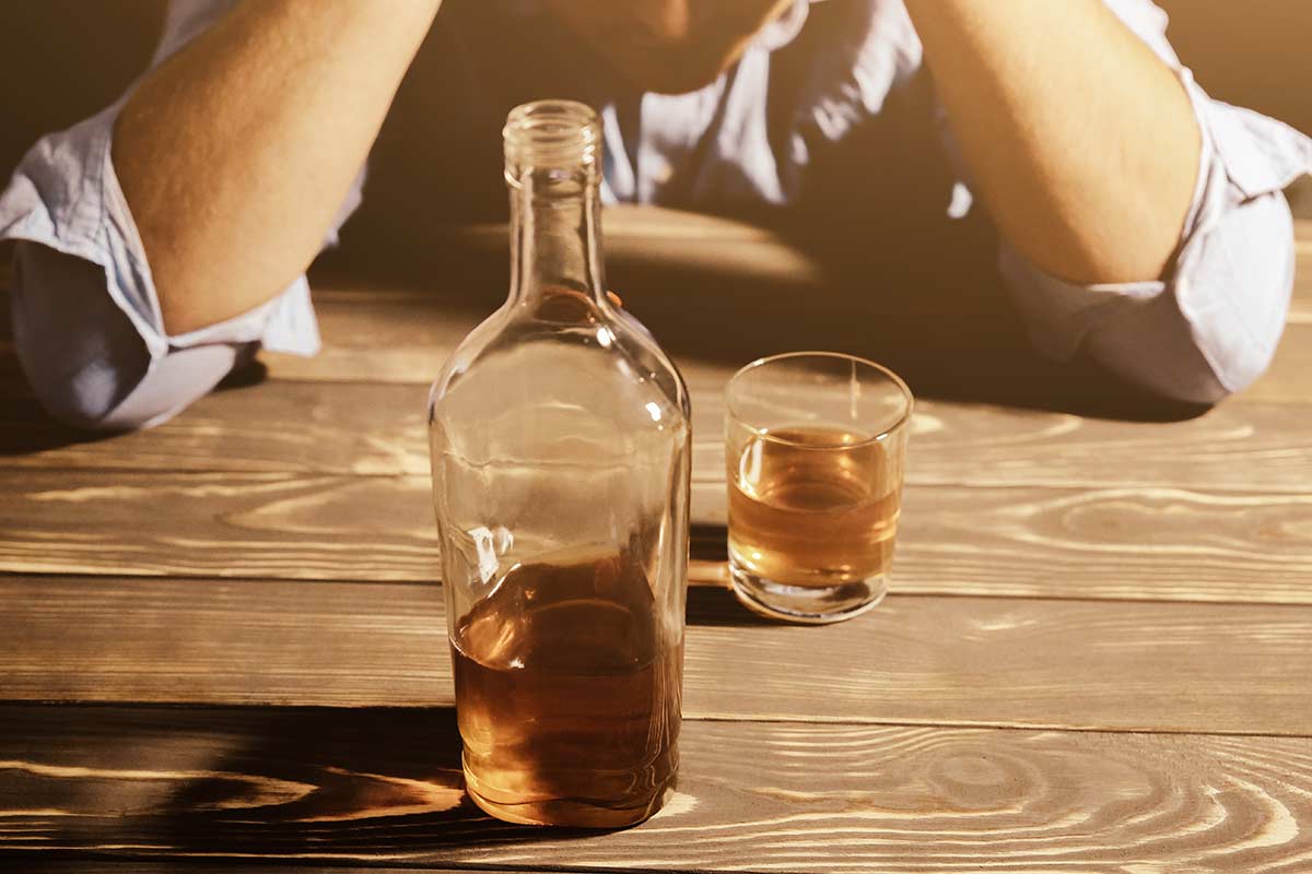 man looking at alcoholic drink struggling with addiction