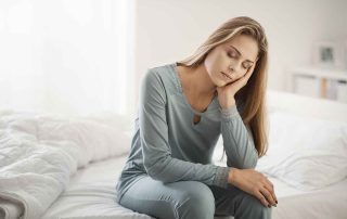 adult women sitting on a bed leaning her head on her hand - detoxing at Meth rehab in Atlanta