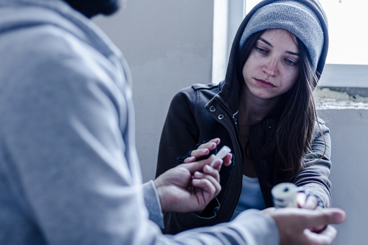 Street drugs being sold by dealer to addicted young woman