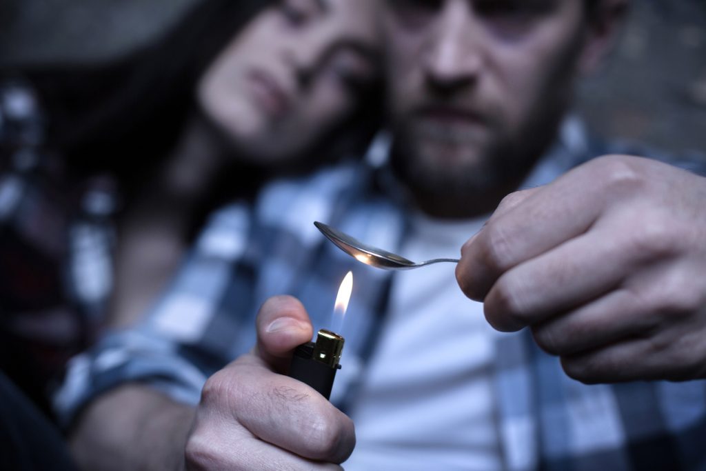 A couple cooking heroin on a spoon suffering from Opiate Addiction in Columbus