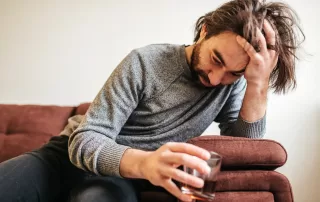 Anticipatory Grief Leading to Alcoholic Tendencies in young man as he stressfully Drinks liquor on couch