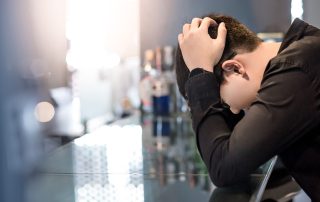 Man at bar with head in hands suffering from mental disorders and substance use