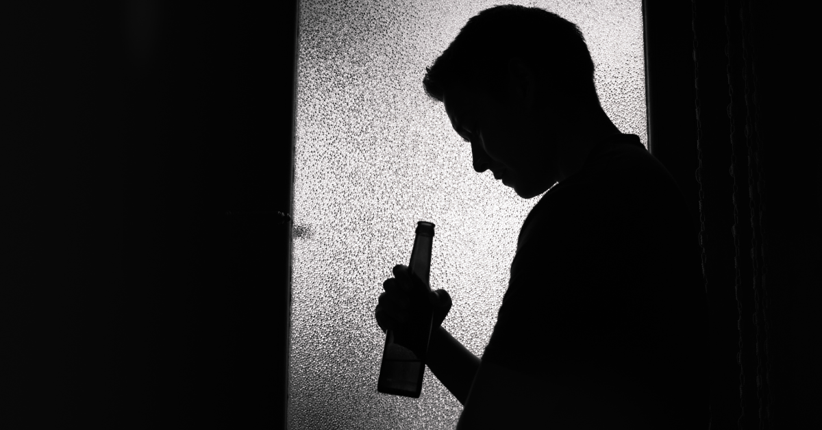 Shadowed silhouette of a man holding a beer bottle. 