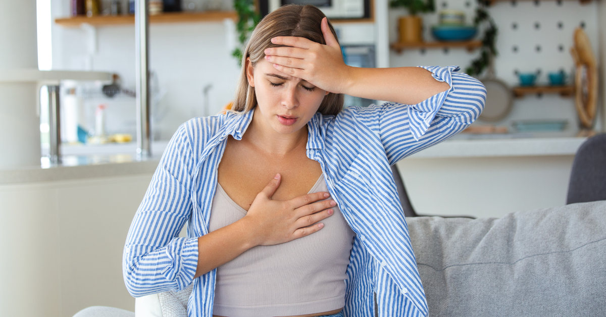A woman holds her chest and head with a pained look on her face.