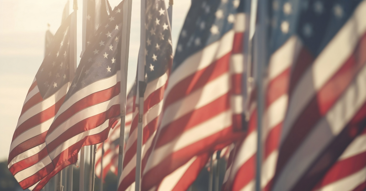 A row of American flags with the sunlight shining between them