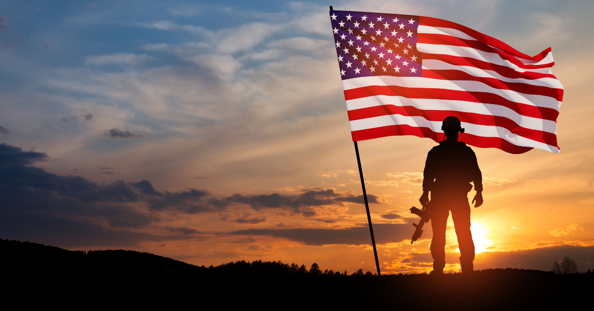 silhouette of a veteran standing in front of an American flag