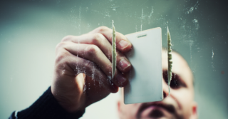 Under shot of a man cutting cocaine into lines with a card.