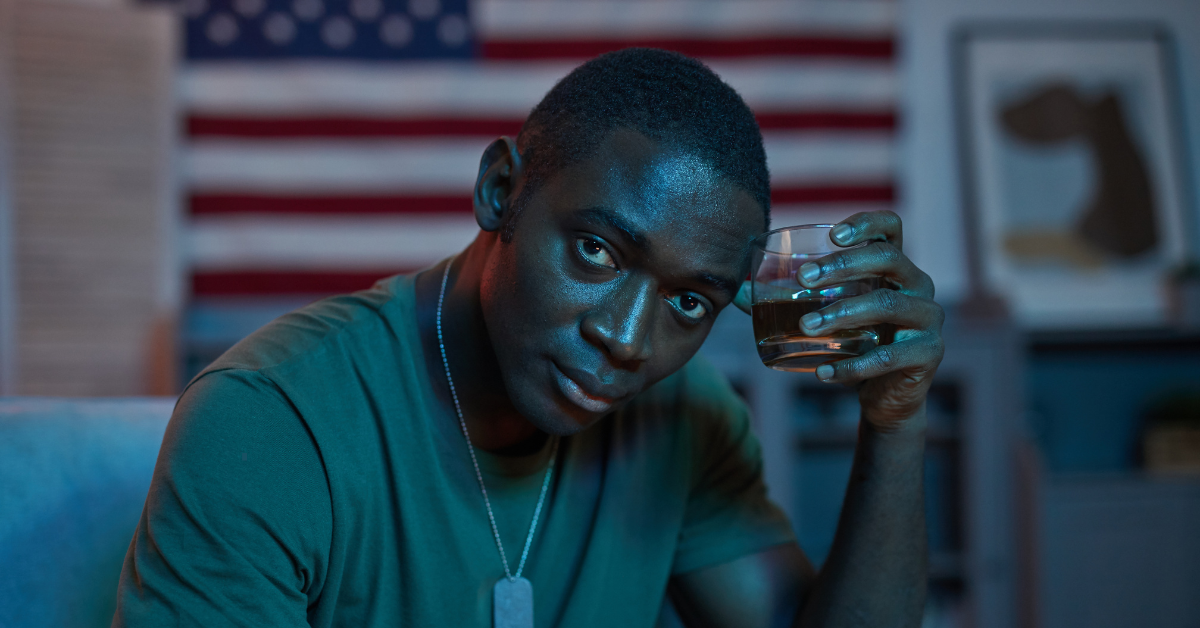 A US soldier holds a filled whiskey glass in his hand.