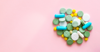 Multicolored pills against a pink background.