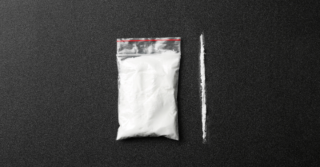 A small bag containing a white powdery substance next to a line of the same substance