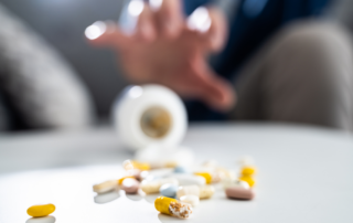 hand reaching out to spilled pills on a table