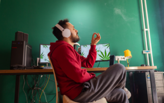 Man in a red jacket smoking marijuana in his home office