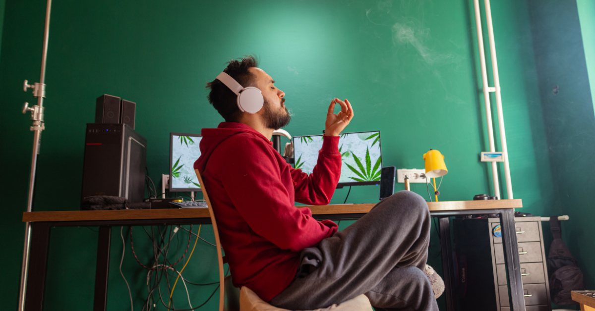 Man in a red jacket smoking marijuana in his home office