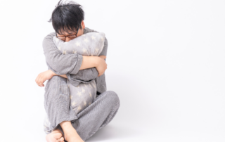 Distressed man in sweatpants hugging a pillow