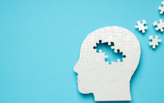 Silhouette of a head made of puzzle pieces with missing pieces floating away, symbolizing memory loss or mental health challenges.