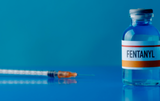 Vial of fentanyl in front of a syringe.