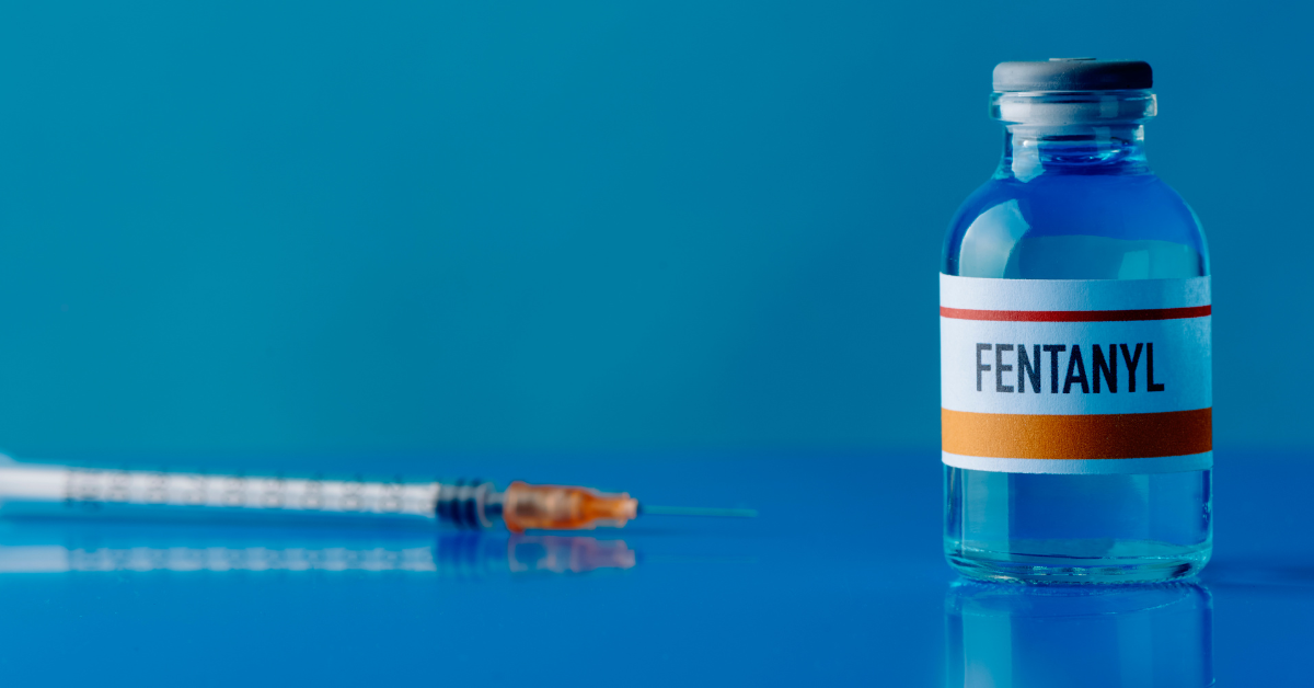 Vial of fentanyl in front of a syringe.