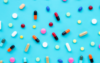 Pills, tablets and capsules in varying colors against a blue background.