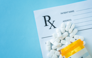 Prescription form with an orange pill bottle and white pills spilling out on a blue background.