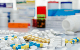 Assorted prescription pills and medication boxes on a table, representing concerns around combining Prozac with Adderall and potential drug interactions.
