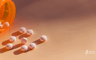 Pink prescription pills spilled from an orange bottle onto a neutral surface, illustrating medication dependence and potential Wellbutrin withdrawal symptoms.