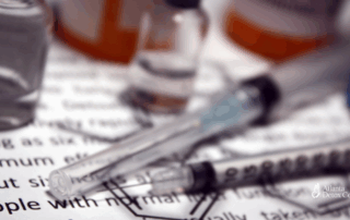 Close-up of syringes and medication vials on printed medical information, representing clinical considerations in Suboxone vs. Methadone treatment for opioid use disorder.